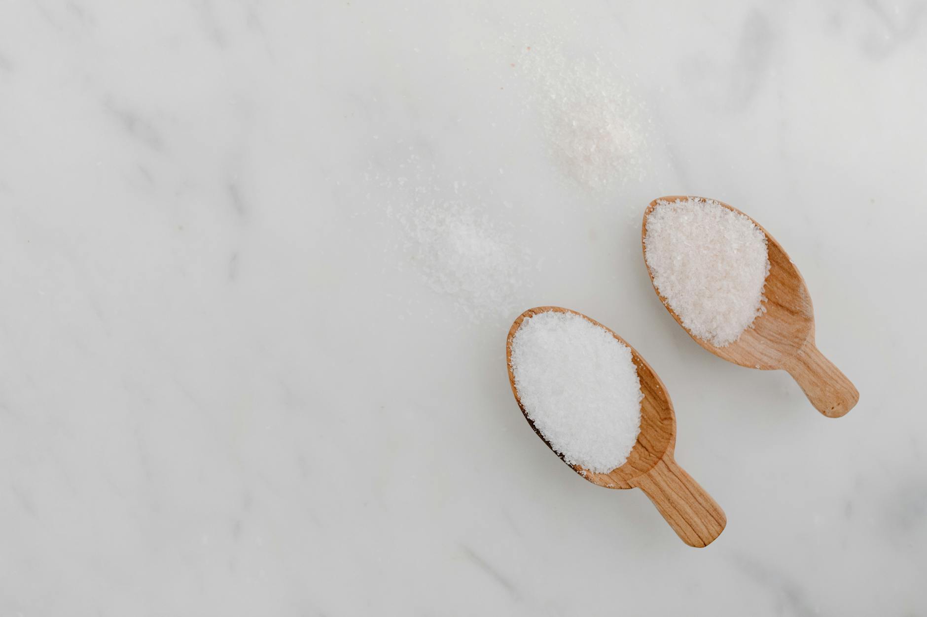 Drewniane łyżki z solą na białym marmurowym blacie z góry