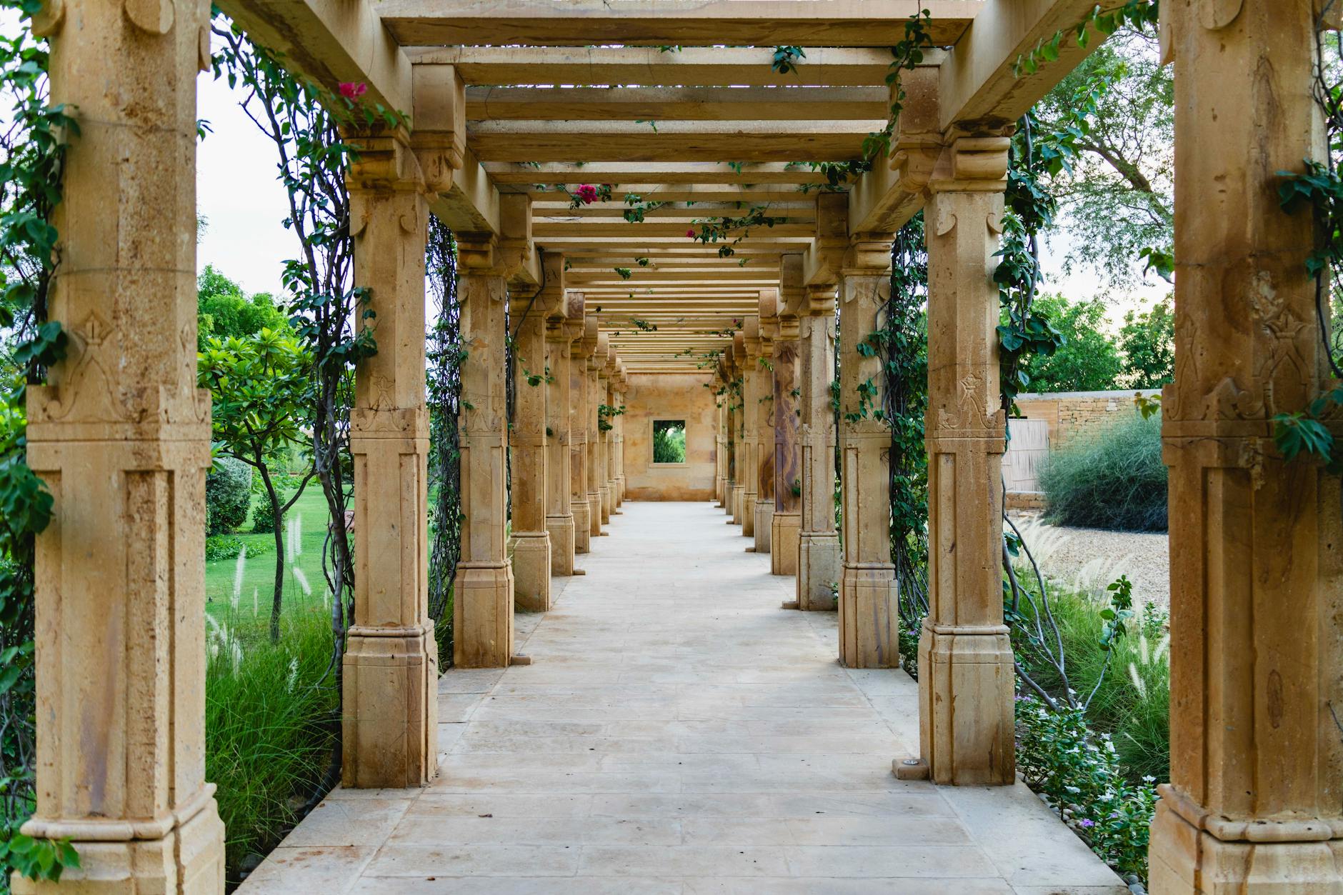 Kamienna ścieżka ogrodowa między kolumnami w słonecznym ogrodzie