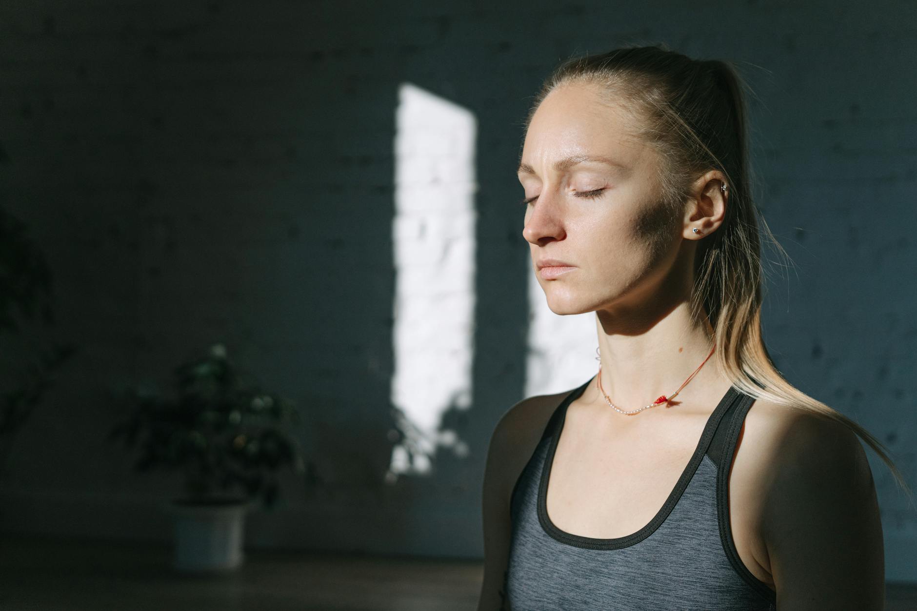 Kobieta medytuje w słonecznym pokoju z zamkniętymi oczami