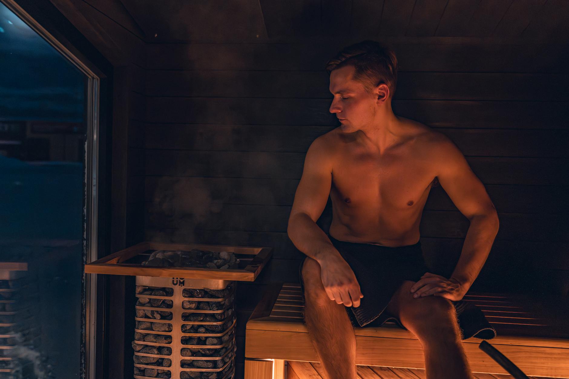 Mężczyzna relaksuje się w nowoczesnej saunie podczas sesji zdrowotnej Mężczyzna relaksuje się w nowoczesnej saunie podczas sesji zdrowotnej