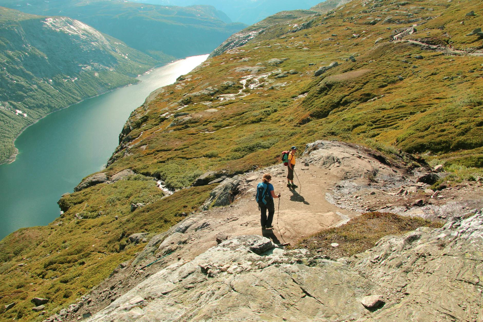 Najpiękniejsze szlaki trekkingowe w Norwegii – przewodnik dla początkujących podróżników Turyści na szlaku trekkingowym wśród norweskich gór nad rzeką
