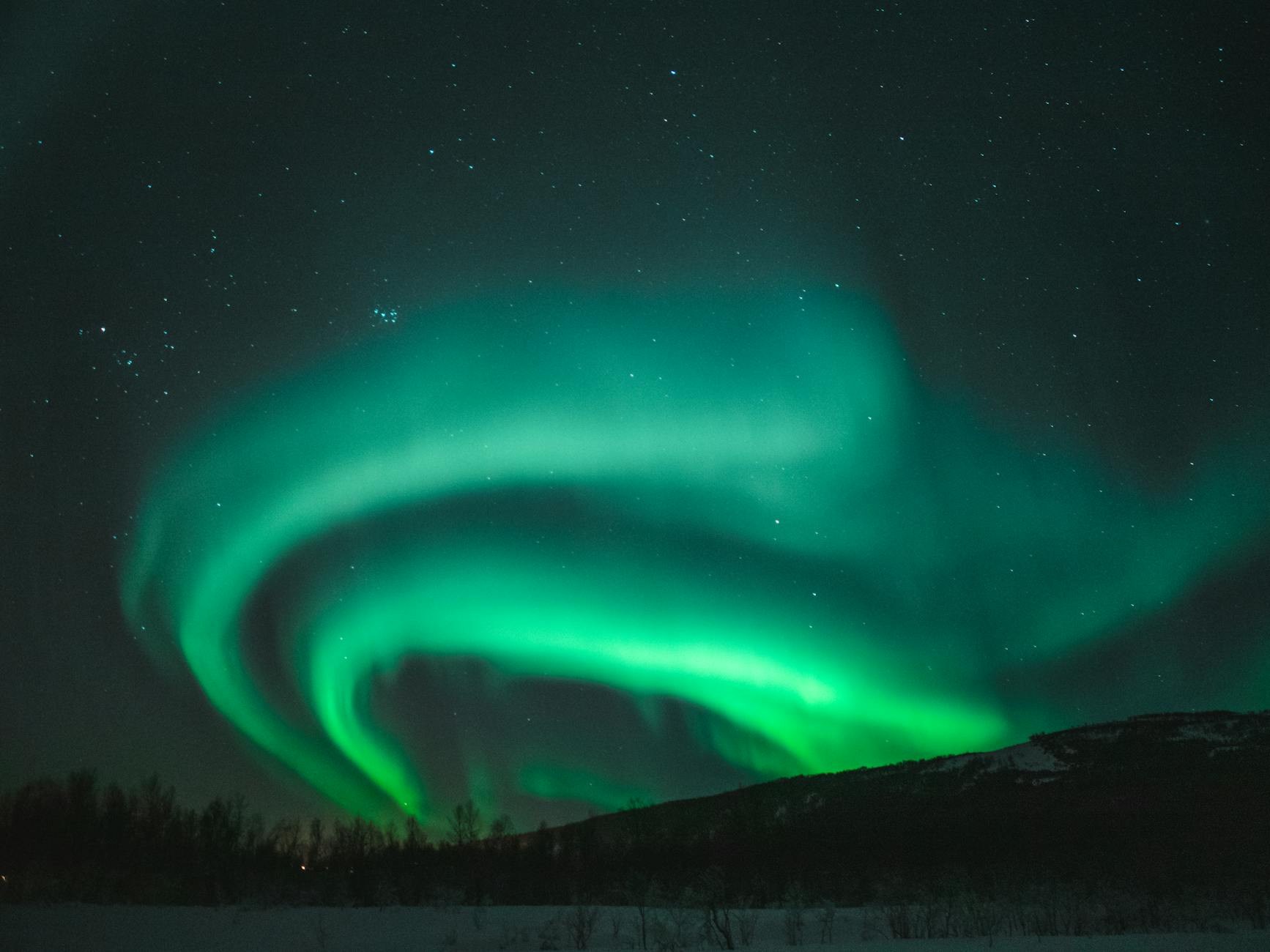 Zorza polarna nad ośnieżonym krajobrazem w Norwegii zimą