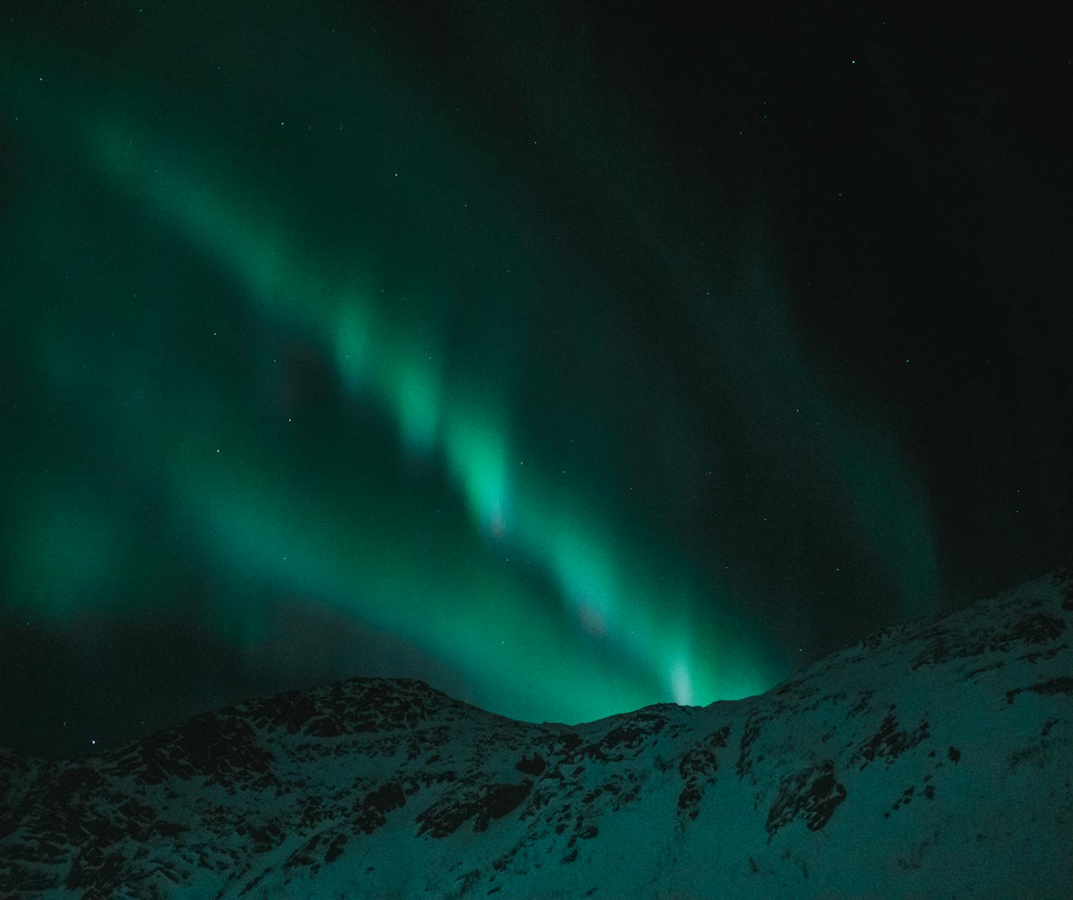 Zorza polarna nad ośnieżonymi górami w zimowej Norwegii Zorza polarna nad ośnieżonymi górami w zimowej Norwegii