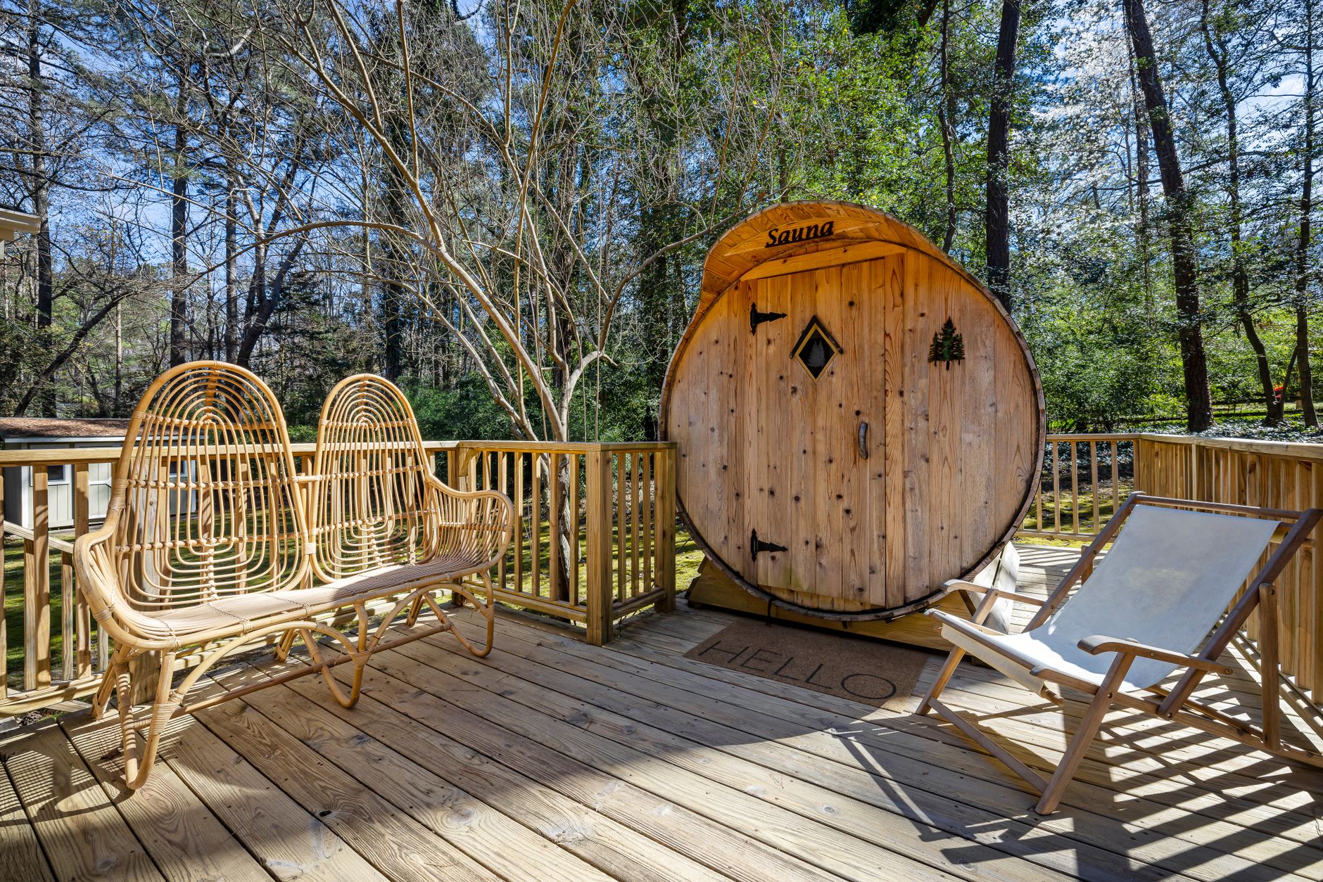 Drewniana sauna na tarasie wśród wysokich drzew w spokojnej okolicy
