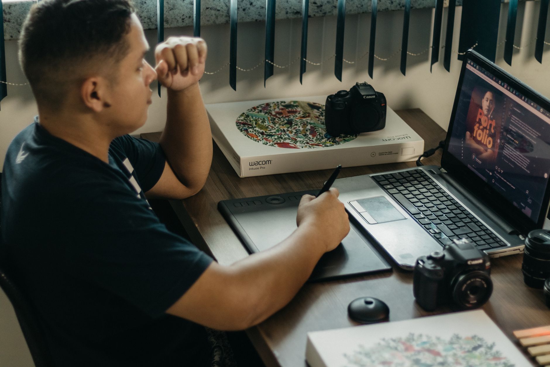 Fotograf edytujący zdjęcia na laptopie i tablecie graficznym w biurze