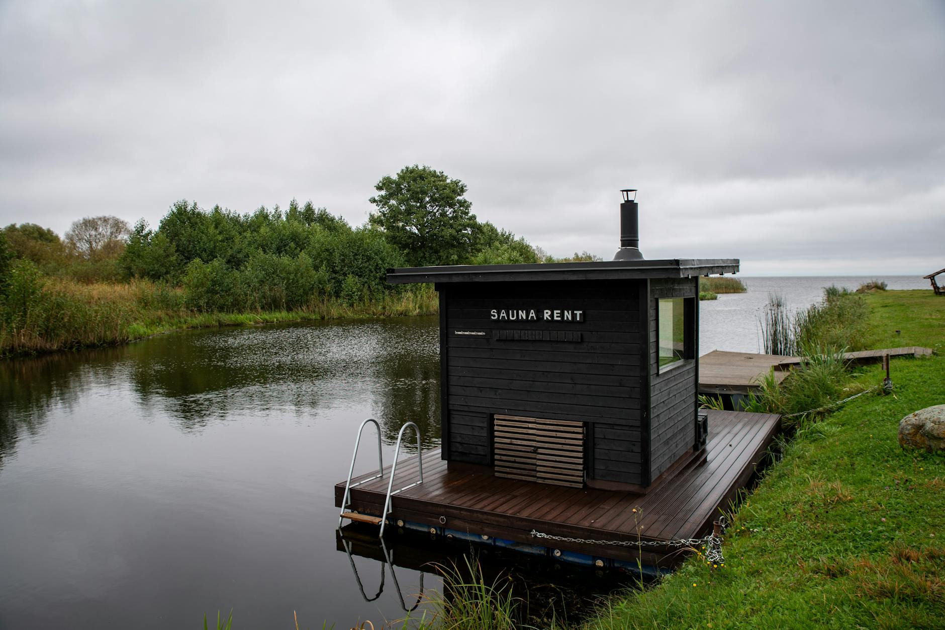 Pływająca sauna nad spokojnym jeziorem otoczonym lasem