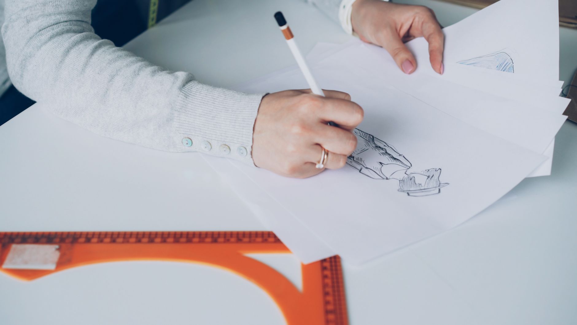 Początkujący grafik rysuje szkice modowe przy biurku w domowym studiu